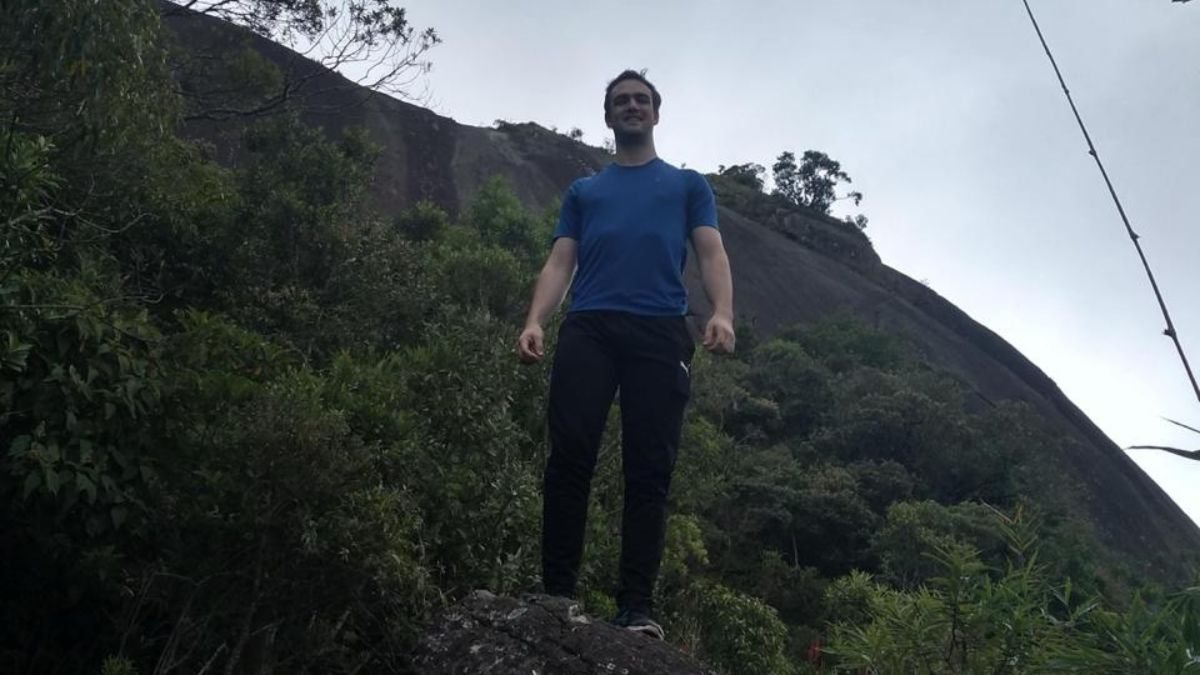 homem em pé na pedra com natureza e montanhas de fundo